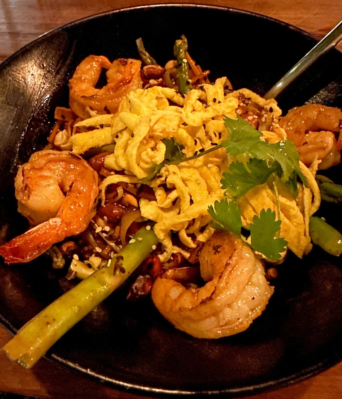 Close-up of a shrimp pad Thai topped with thin strips of egg, fresh cilantro, and vegetables, served at Aluxes, a restaurant attached to the Casa Barbara Hotel on Holbox Island.