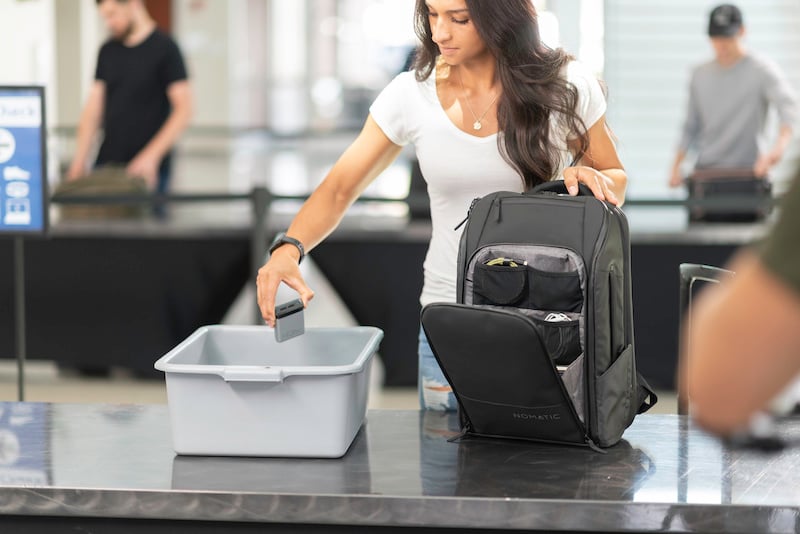 solo female traveler packing her gear into the Nomatic Travel Backpack